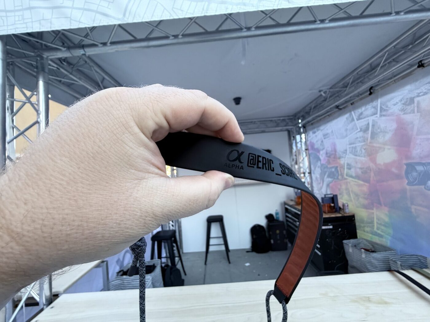 Hand holding a custom-printed camera strap made on site at an event tent